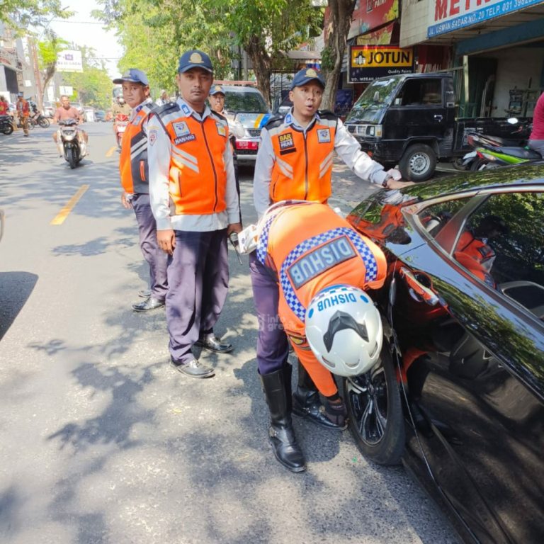 Petugas Dishub Gresik saat mengembosi roda mobil yang parkir sembarangan di Jalan Usman Sadar Gresik. (Foto: Ist/Infogresik)