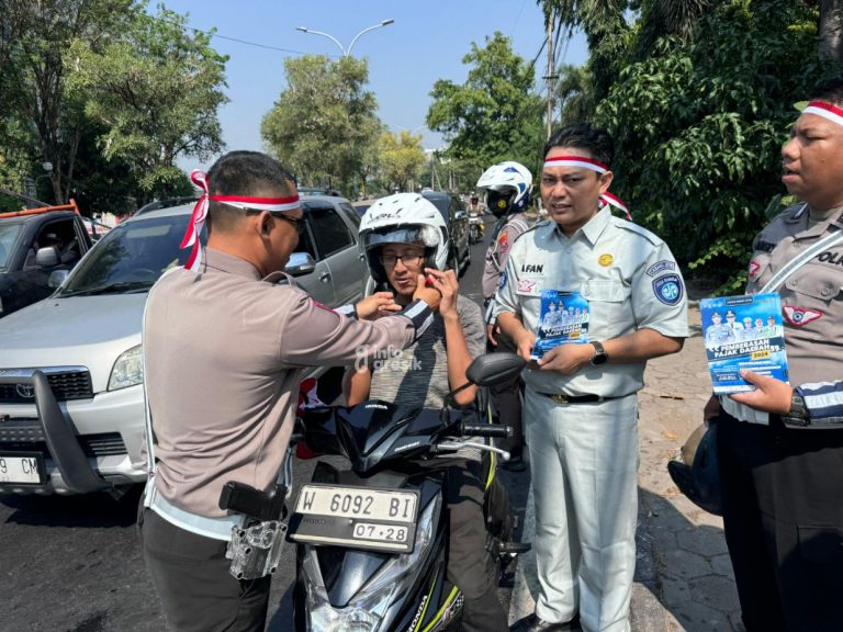 Kanit Kamsel Satlantas Polres Gresik saat memasangkan helm ke pengendara didampingi perwakilan Jasa Raharja. (Foto: Ist/Infogresik)
