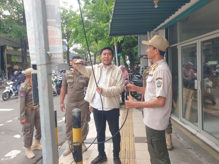 Wakil Ketua DPRD Gresik Lutfi Dhawam didampingi Satpol PP Gresik saat memotong kabel penyedia internet yang diletakan sembarangan di Perlimaan Sukorame. (Foto: Khanif Rosidin/Infogresik)