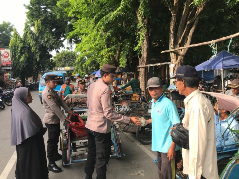 Anggota Reskrim Polsek Sidayu Bripda Bintang Samudera dibonceng Kapolsek Sidayu AKP Khairul Alam berkeliling Alun-alun sambil membagikan nasi bungkus. (Foto: Khanif Rosidin/Infogresik)