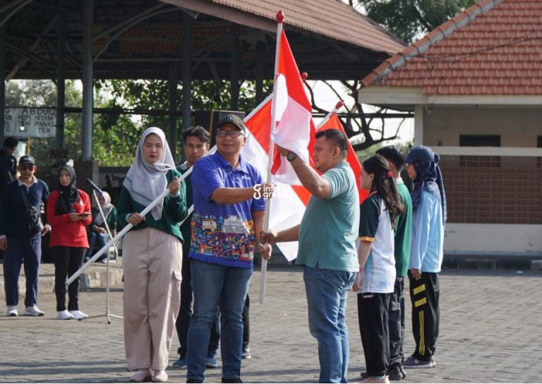 Wabup Gresik dr. Asluchul Alif menyerahkan bendera merah putih kepada Lurah Lumpur Eka Prapangasta. (Foto: Ist/Infogresik)