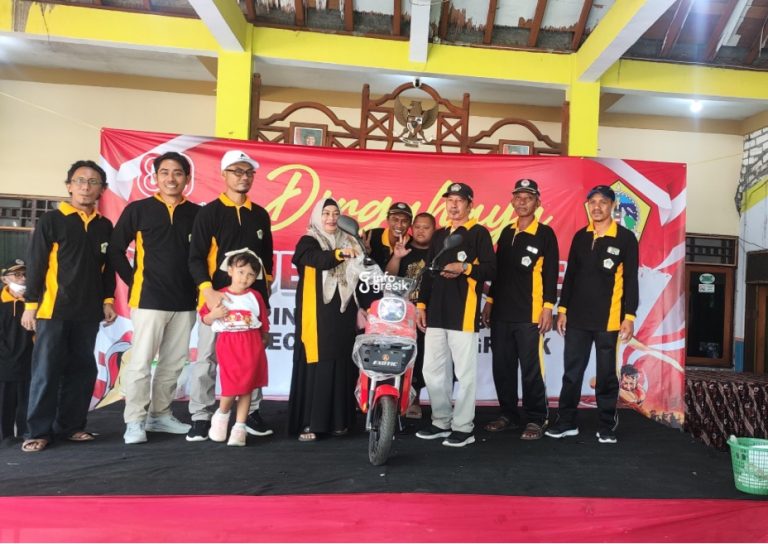 Kepala Desa Sembunganyar, Khobir, menyerahkan hadiah motor listrik kepada pemenang undian jalan sehat. (Foto: Ist/Infogresik)