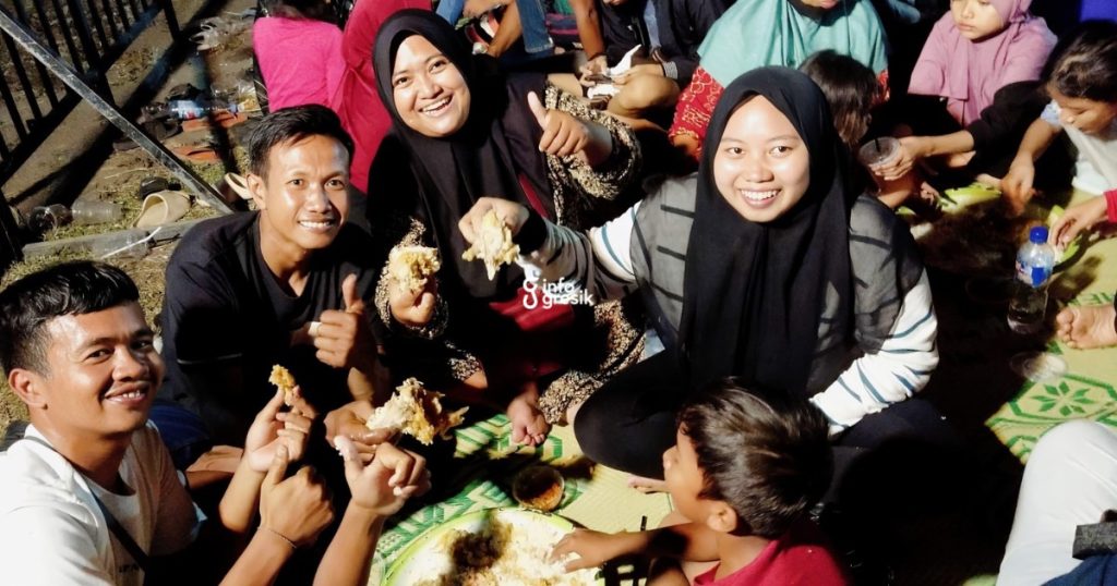 Warga menikmati olahan menu ayam gratis yang dibagikan pada tradisi Sedekah Bumi Desa Sidowungu. (Foto: Ist/Infogresik)