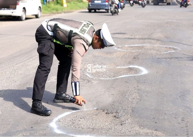 Petugas Satlantas Polres Gresik melakukan penyemprotan cat penanda pada jalan berlubang di kawasan Manyar sebagai upaya meningkatkan kewaspadaan pengguna jalan. (Foto: Ist/Infogresik)