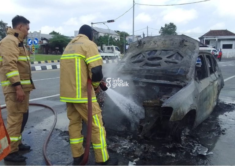 Petugas Damkarla Pos Driyorejo melakukan pemadaman mobil yang terbakar di pintu masuk Tol Belahanrejo, Kedamean. (Foto: Ist/Infogresik)