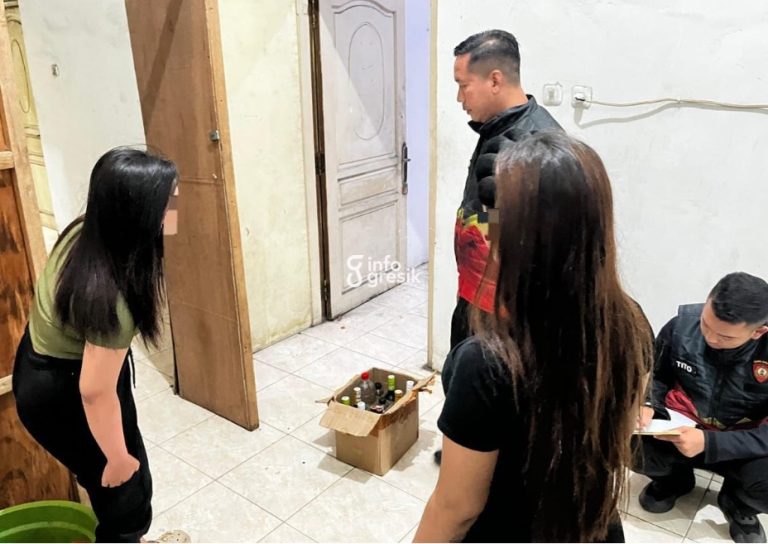 Petugas Satuan Samapta Polres Gresik saat mengamankan puluhan botol minuman keras yang disembunyikan di salah satu warung di Desa Roomo, Kecamatan Manyar. (Foto: Ist/Infogresik)